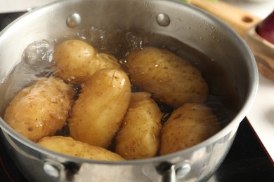 Photo of Boiling potatoes in metal pot on stove, closeup