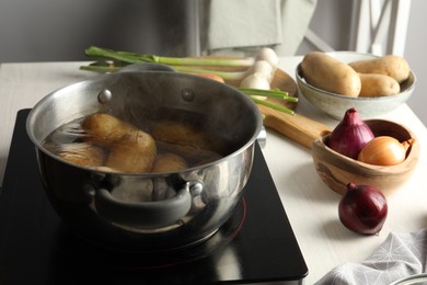 Photo of Boiling potatoes in metal pot on stove