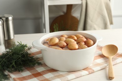 Photo of Raw potatoes in pot with water, dill and spoon on table