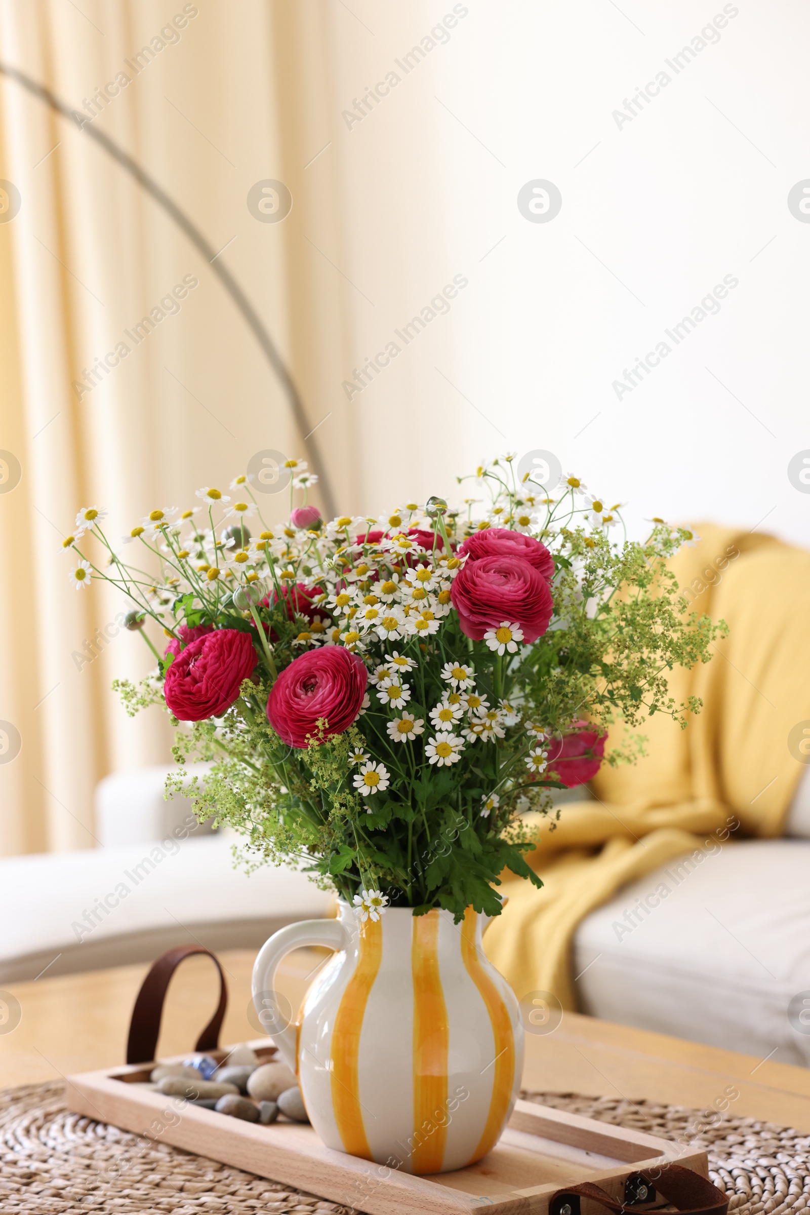 Photo of Beautiful ranunculus flowers and chamomiles in vase on table indoors