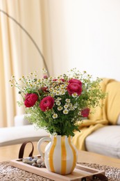 Photo of Beautiful ranunculus flowers and chamomiles in vase on table indoors