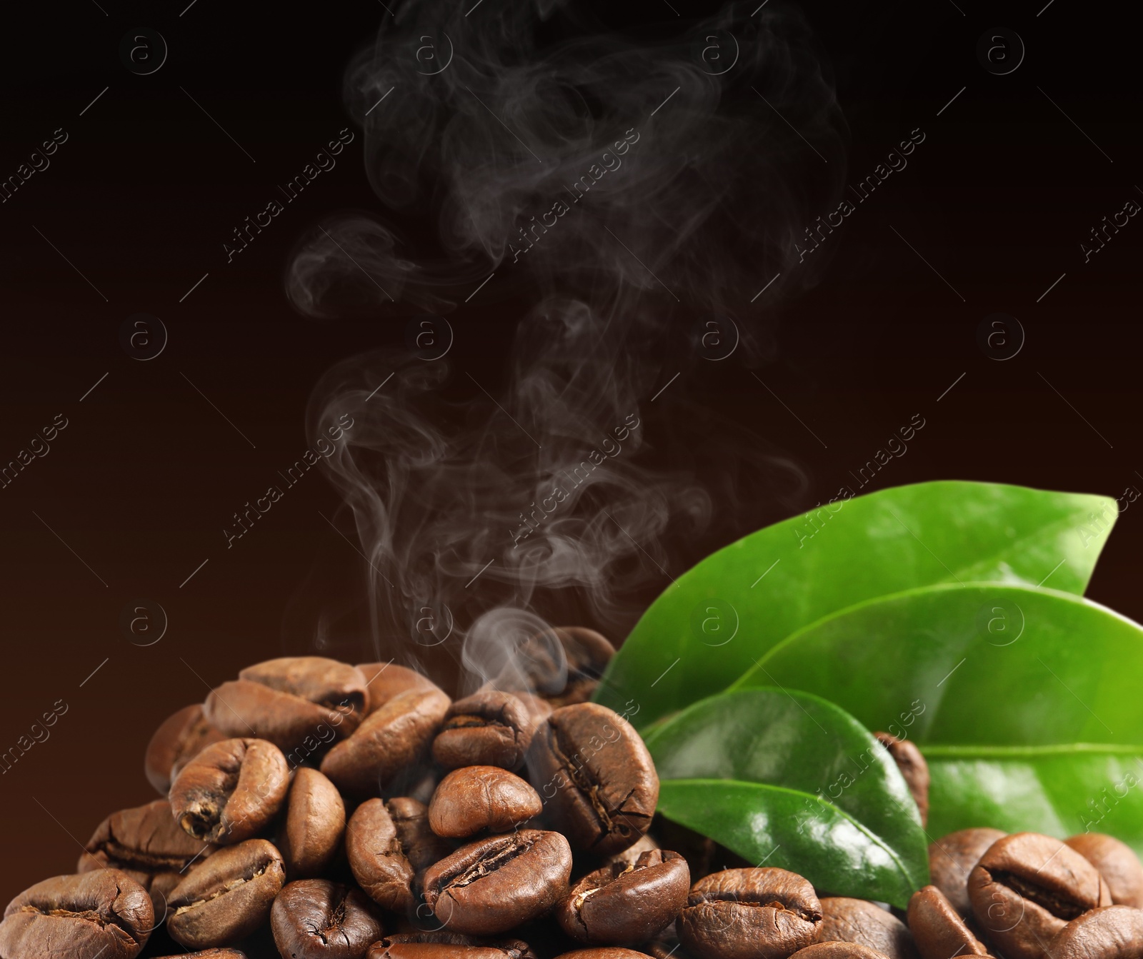 Image of Freshly roasted coffee beans and green leaves on dark background