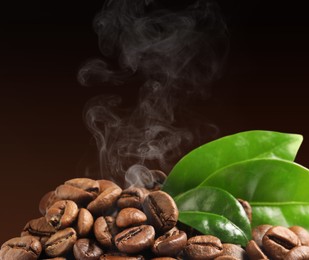 Image of Freshly roasted coffee beans and green leaves on dark background