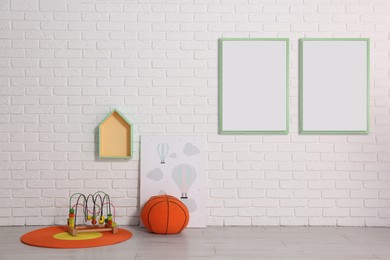 Room for child with blank pictures on white brick wall. Interior design