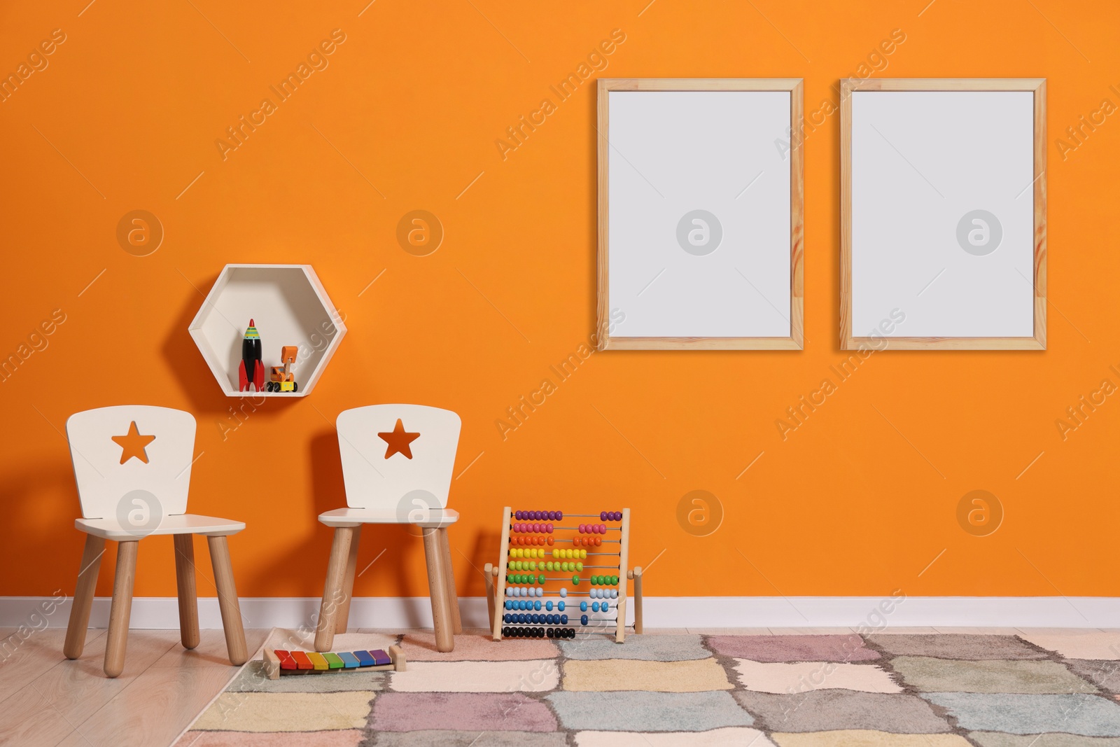 Image of Room for child with blank pictures on orange wall. Interior design