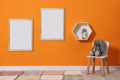 Image of Room for child with blank pictures on orange wall. Interior design
