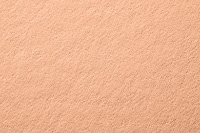 Peach fuzz color paper, closeup. Trendy shade of 2024 year