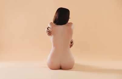 Nude woman on beige background, back view