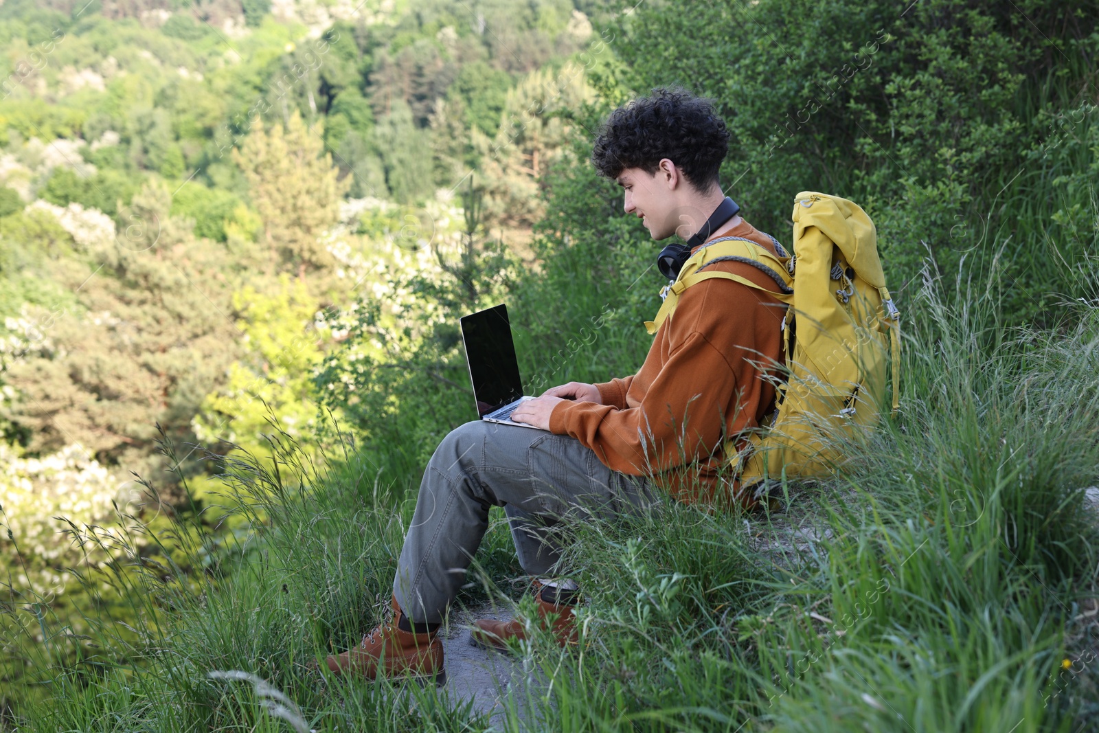 Photo of Travel blogger with backpack using laptop outdoors