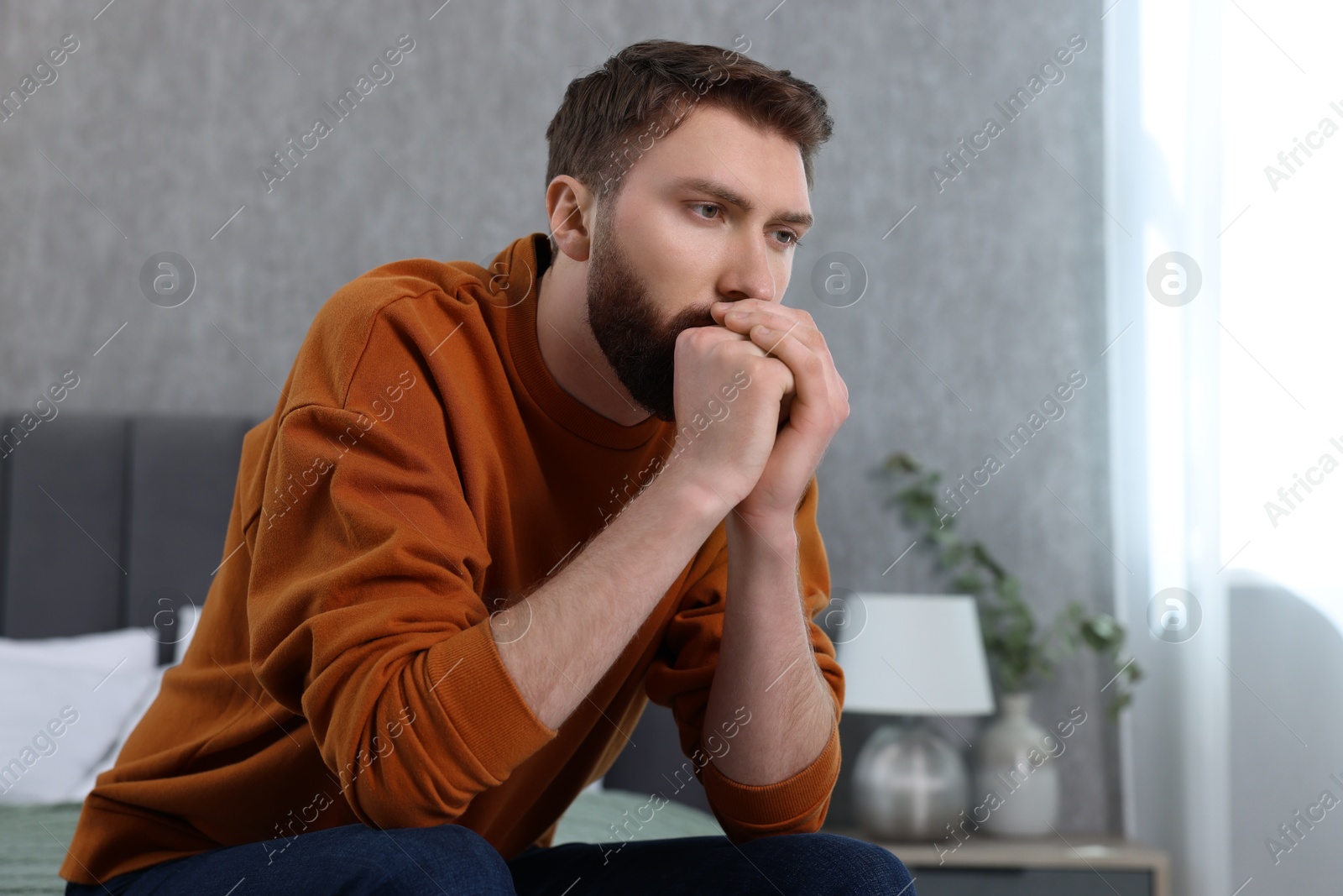 Photo of Loneliness concept. Sad man sitting on bed at home