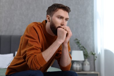 Loneliness concept. Sad man sitting on bed at home