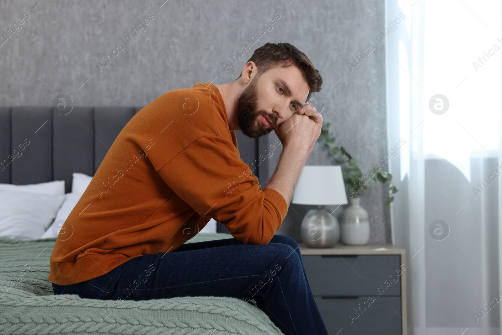 Photo of Loneliness concept. Sad man sitting on bed at home