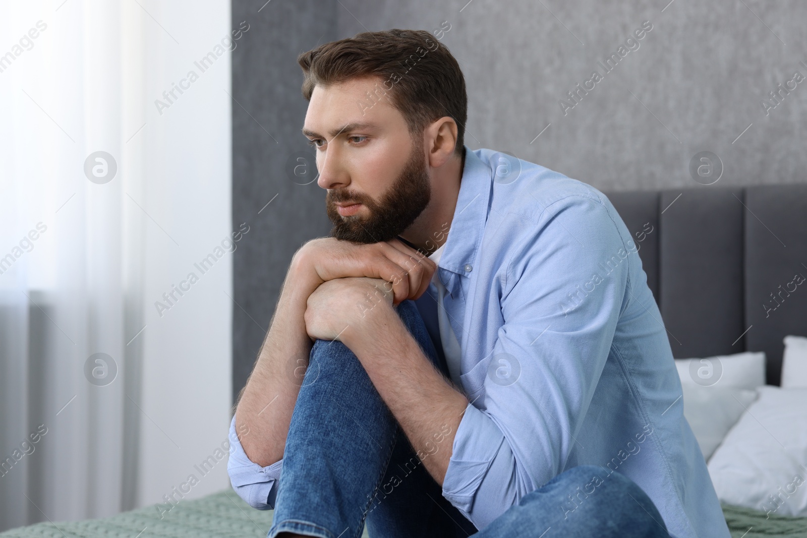 Photo of Loneliness concept. Sad man sitting on bed at home