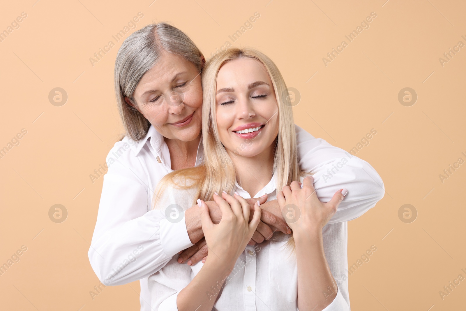 Photo of Family portrait of young woman and her mother on beige background