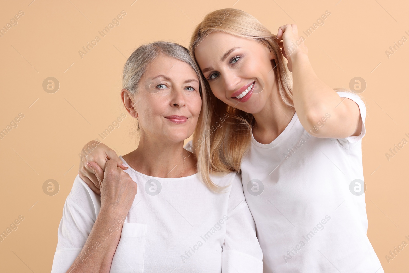 Photo of Family portrait of young woman and her mother on beige background