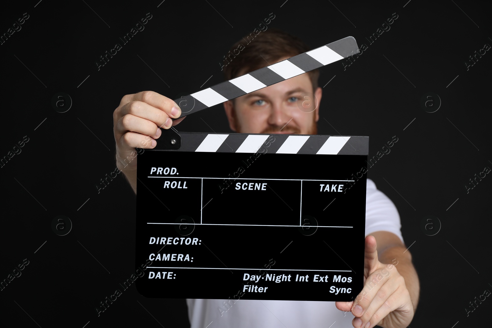 Photo of Making movie. Man with clapperboard on black background, selective focus