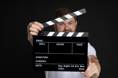 Photo of Making movie. Man with clapperboard on black background, selective focus