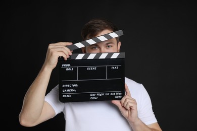 Photo of Making movie. Man with clapperboard on black background