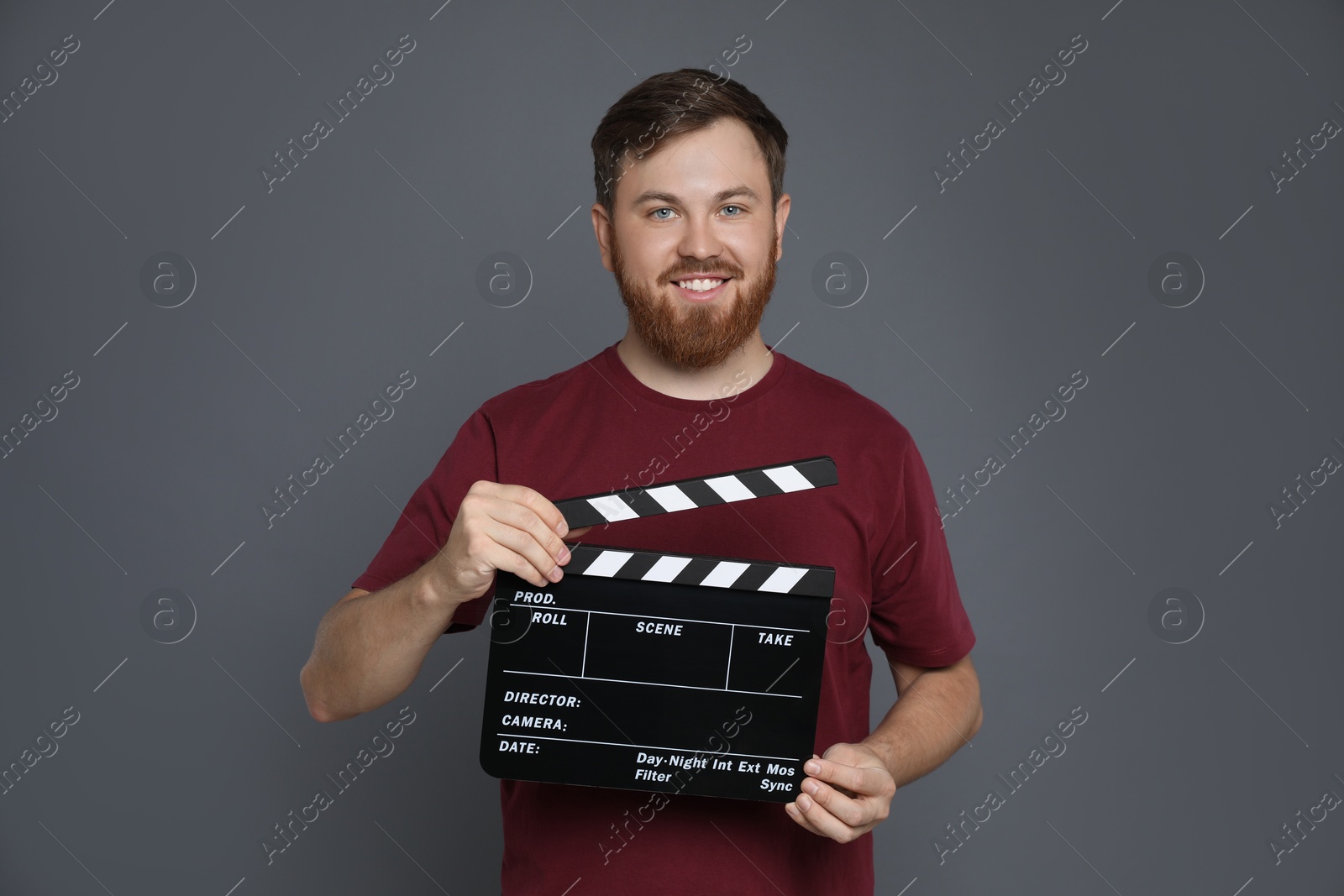 Photo of Making movie. Smiling man with clapperboard on grey background