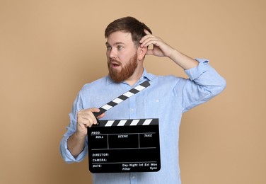Making movie. Man with clapperboard on beige background
