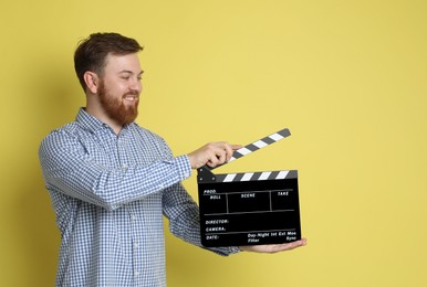 Photo of Making movie. Smiling man with clapperboard on yellow background. Space for text