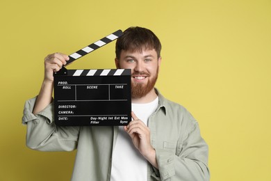 Photo of Making movie. Smiling man with clapperboard on yellow background