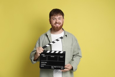 Photo of Making movie. Smiling man with clapperboard on yellow background