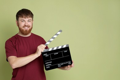 Photo of Making movie. Smiling man with clapperboard on green background. Space for text