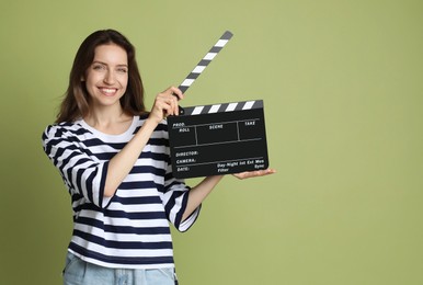 Photo of Making movie. Smiling woman with clapperboard on green background. Space for text