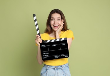 Making movie. Smiling woman with clapperboard on green background