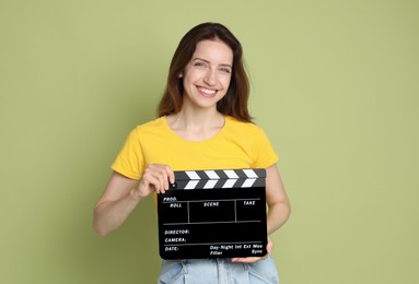 Making movie. Smiling woman with clapperboard on green background