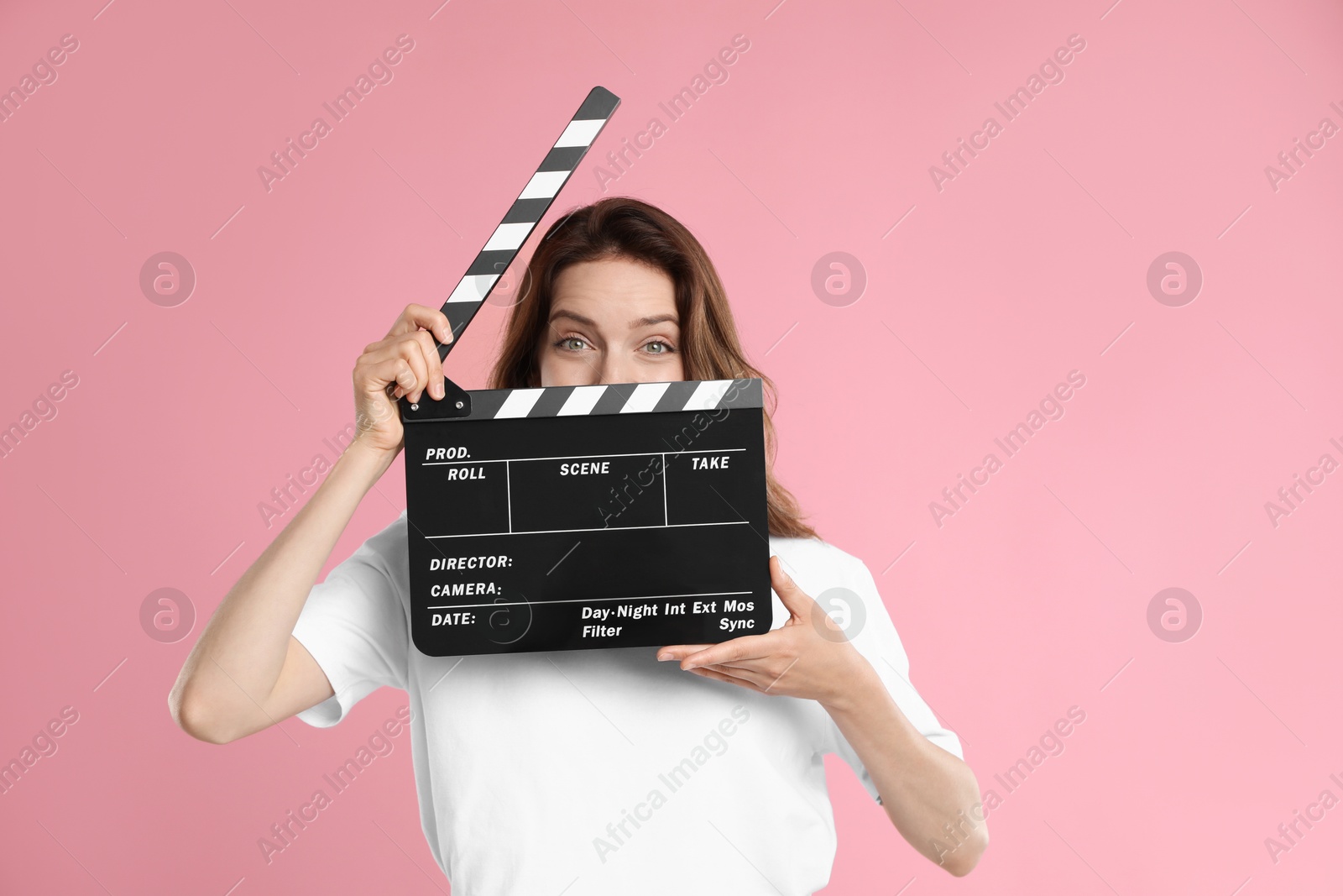 Photo of Making movie. Woman with clapperboard on pink background