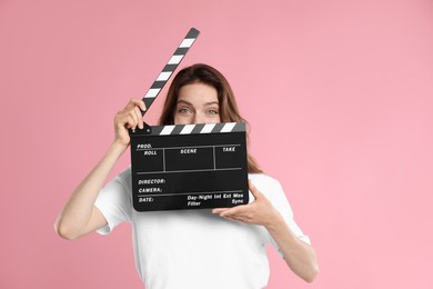 Making movie. Woman with clapperboard on pink background