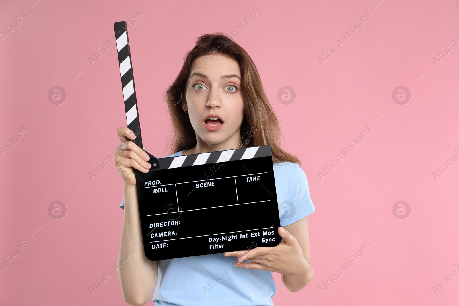 Photo of Making movie. Scared woman with clapperboard on pink background