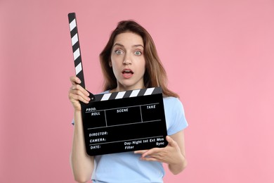 Photo of Making movie. Scared woman with clapperboard on pink background