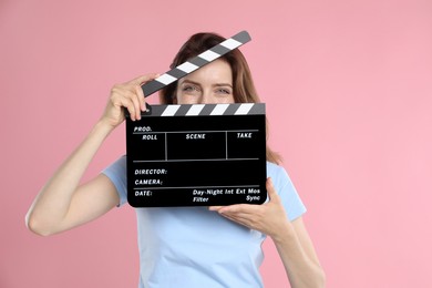 Making movie. Woman with clapperboard on pink background