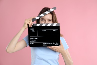 Photo of Making movie. Woman with clapperboard on pink background