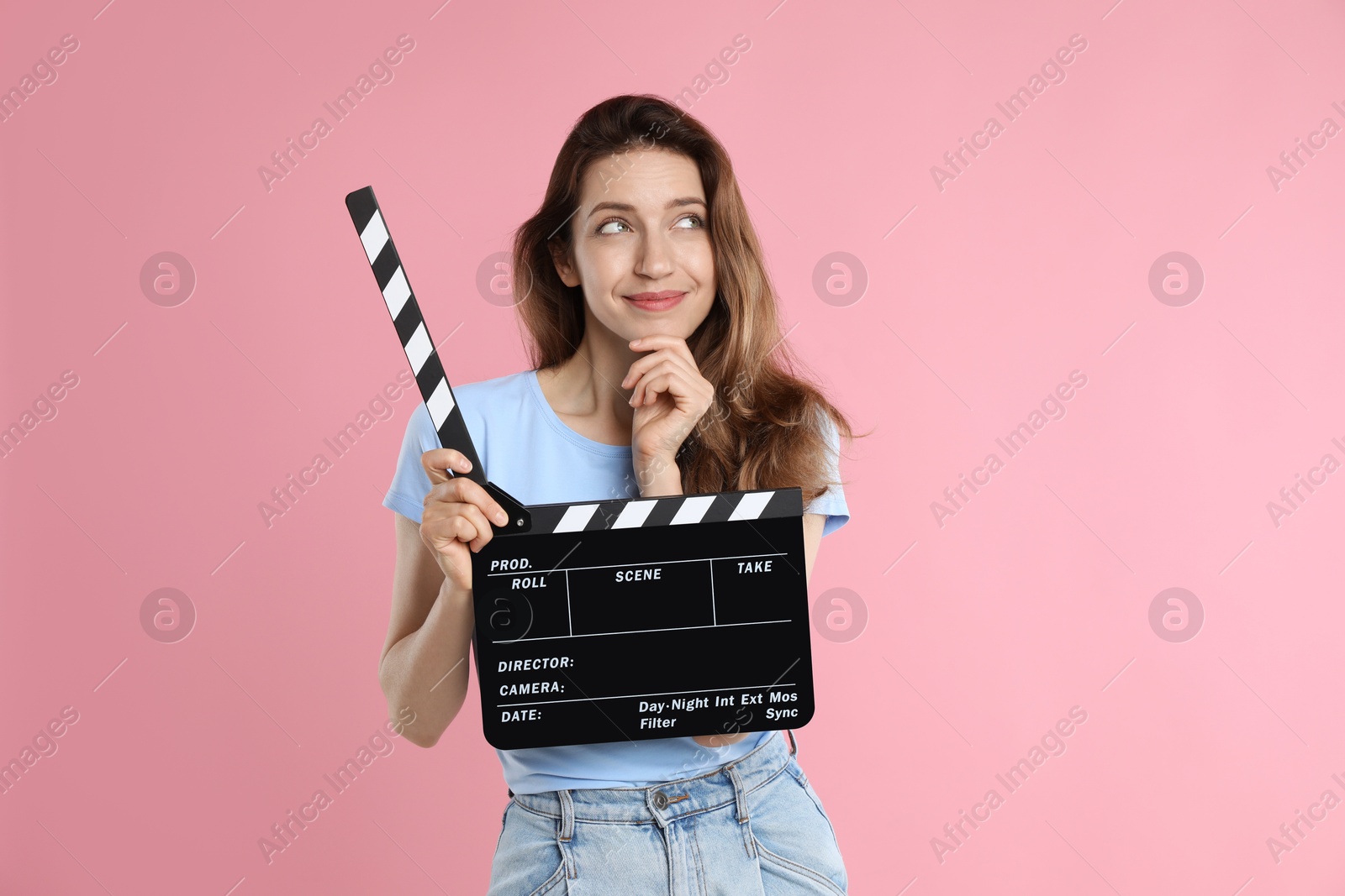 Photo of Making movie. Thoughtful woman with clapperboard on pink background