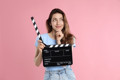 Making movie. Thoughtful woman with clapperboard on pink background
