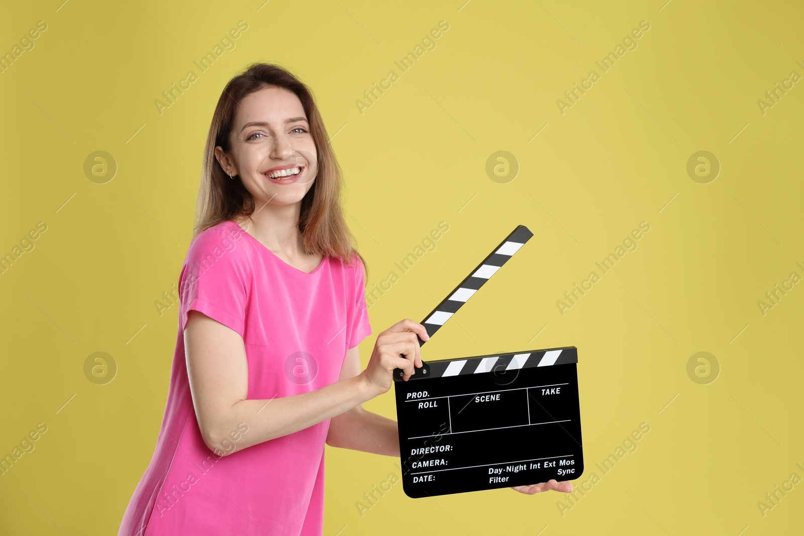 Photo of Making movie. Smiling woman with clapperboard on yellow background