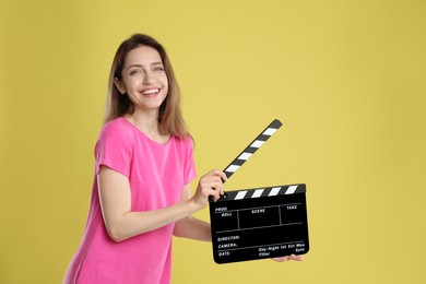 Making movie. Smiling woman with clapperboard on yellow background