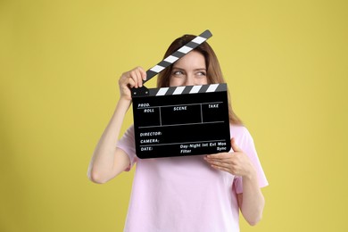 Making movie. Woman with clapperboard on yellow background