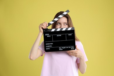 Photo of Making movie. Woman with clapperboard on yellow background