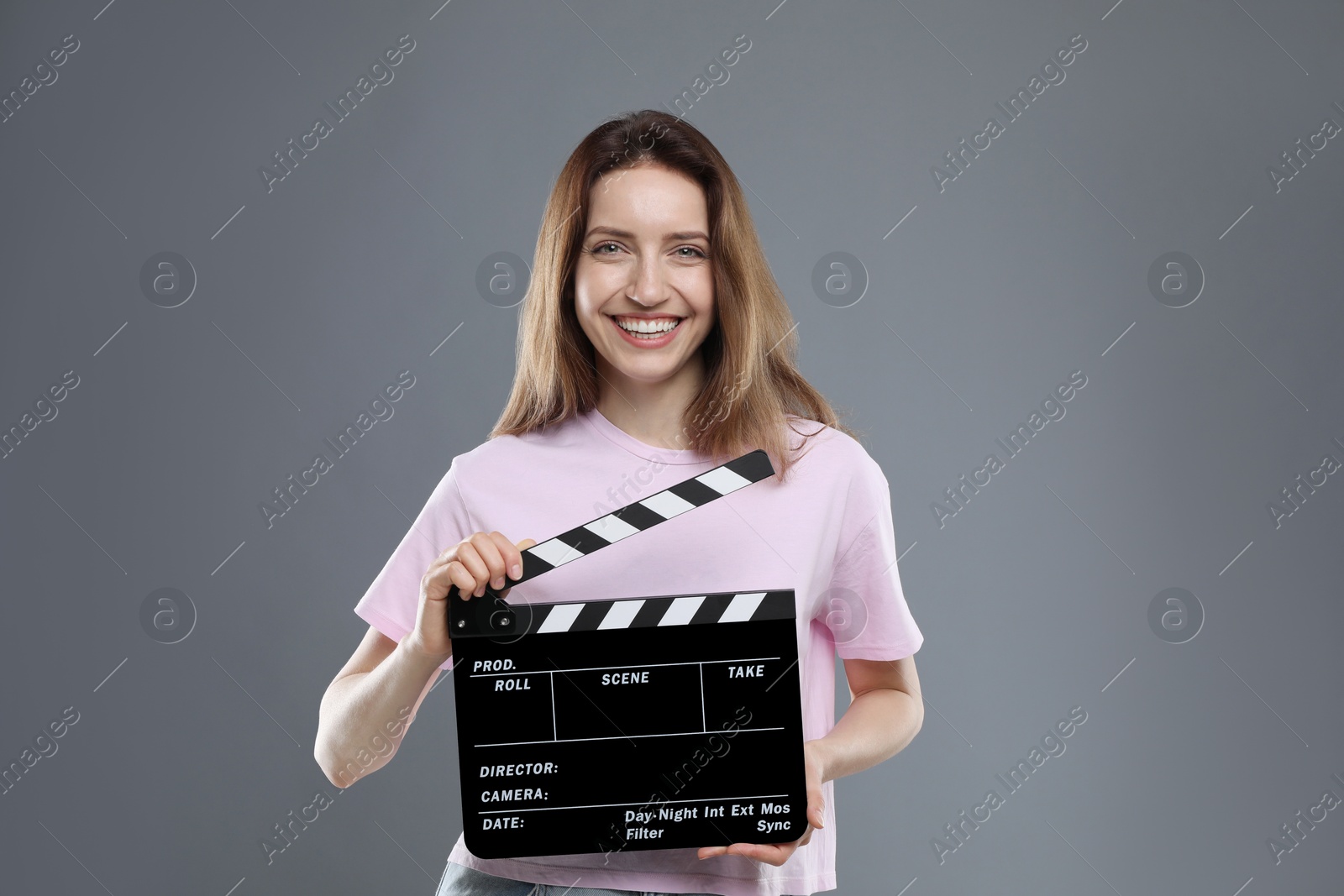 Photo of Making movie. Smiling woman with clapperboard on grey background