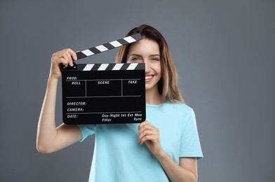 Photo of Making movie. Smiling woman with clapperboard on grey background