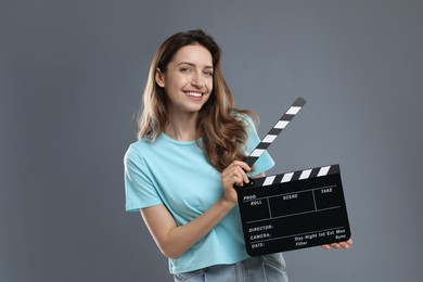 Photo of Making movie. Smiling woman with clapperboard on grey background