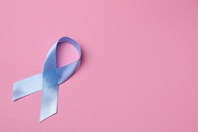 Photo of International Psoriasis Day. Light blue ribbon as symbol of support on pink background, top view. Space for text