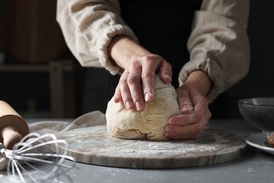 Woman kneading dough at grey table, closeup