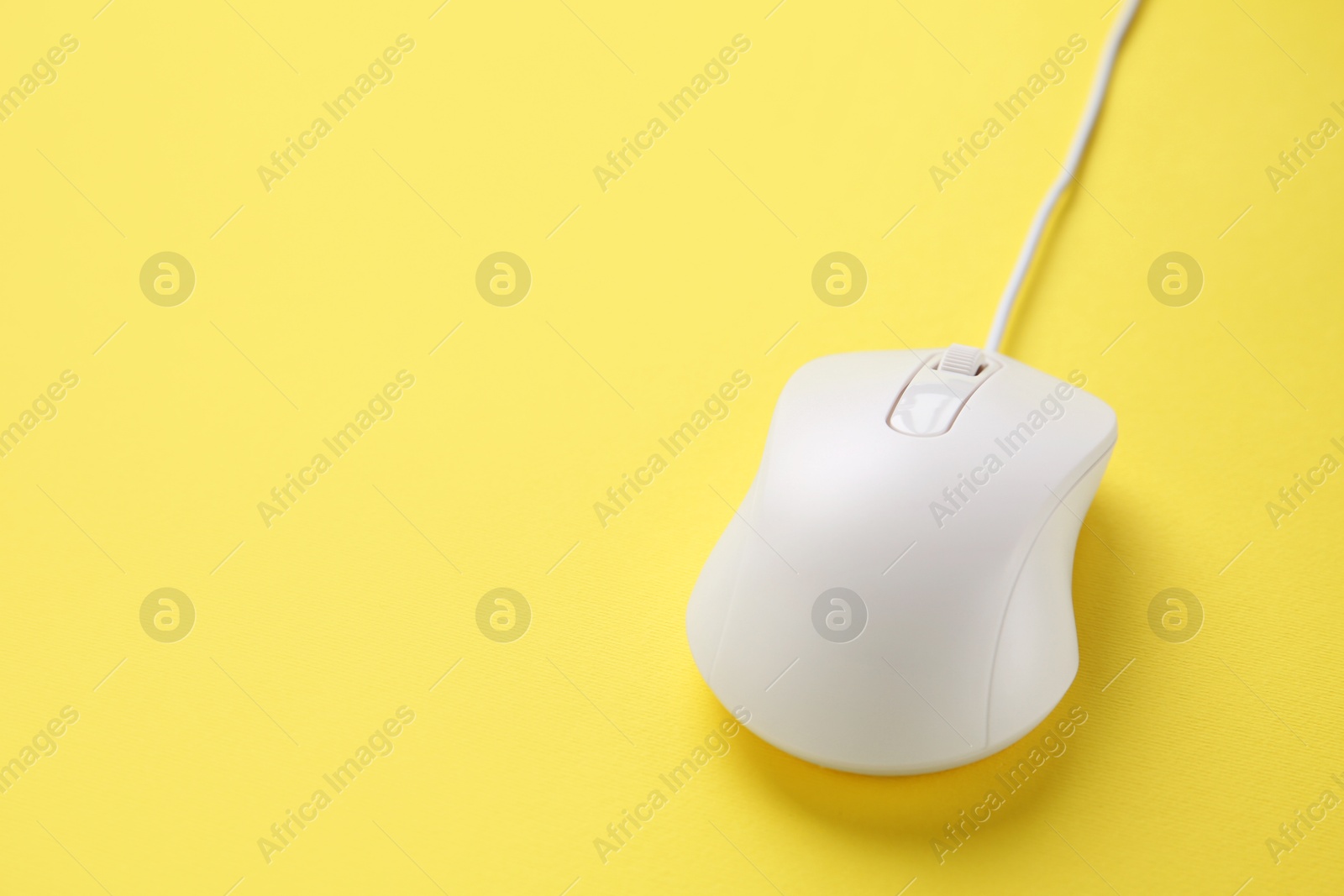 Photo of One wired mouse on yellow background, closeup. Space for text