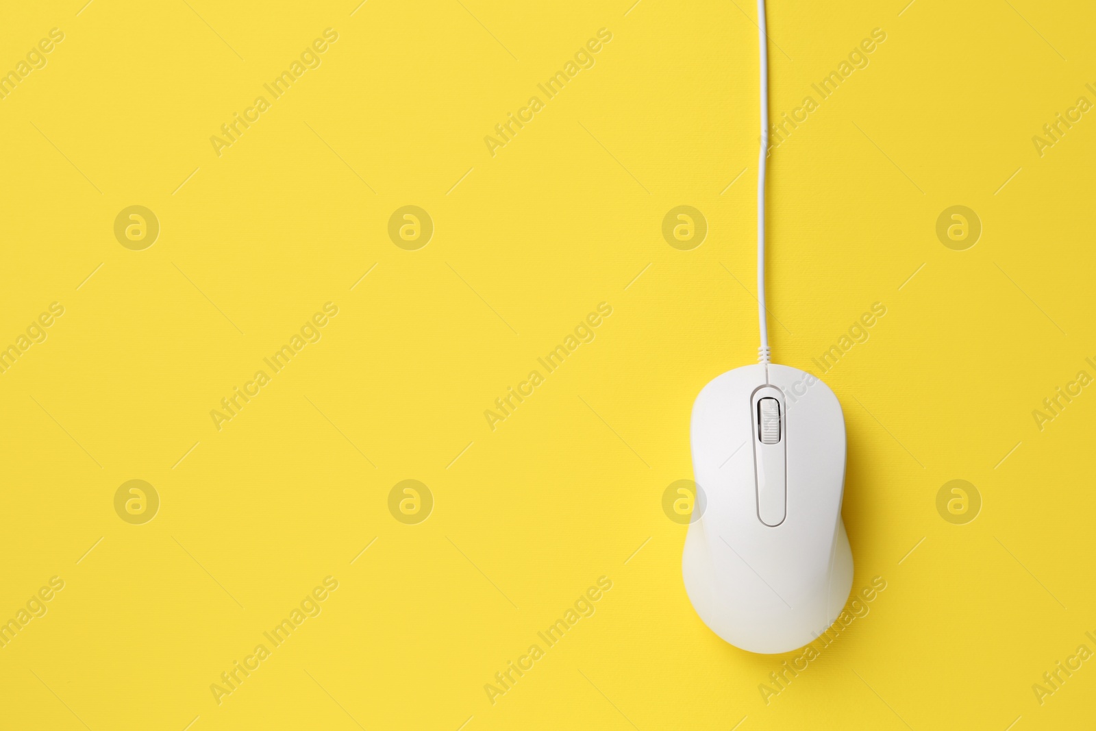 Photo of One wired mouse on yellow background, top view. Space for text